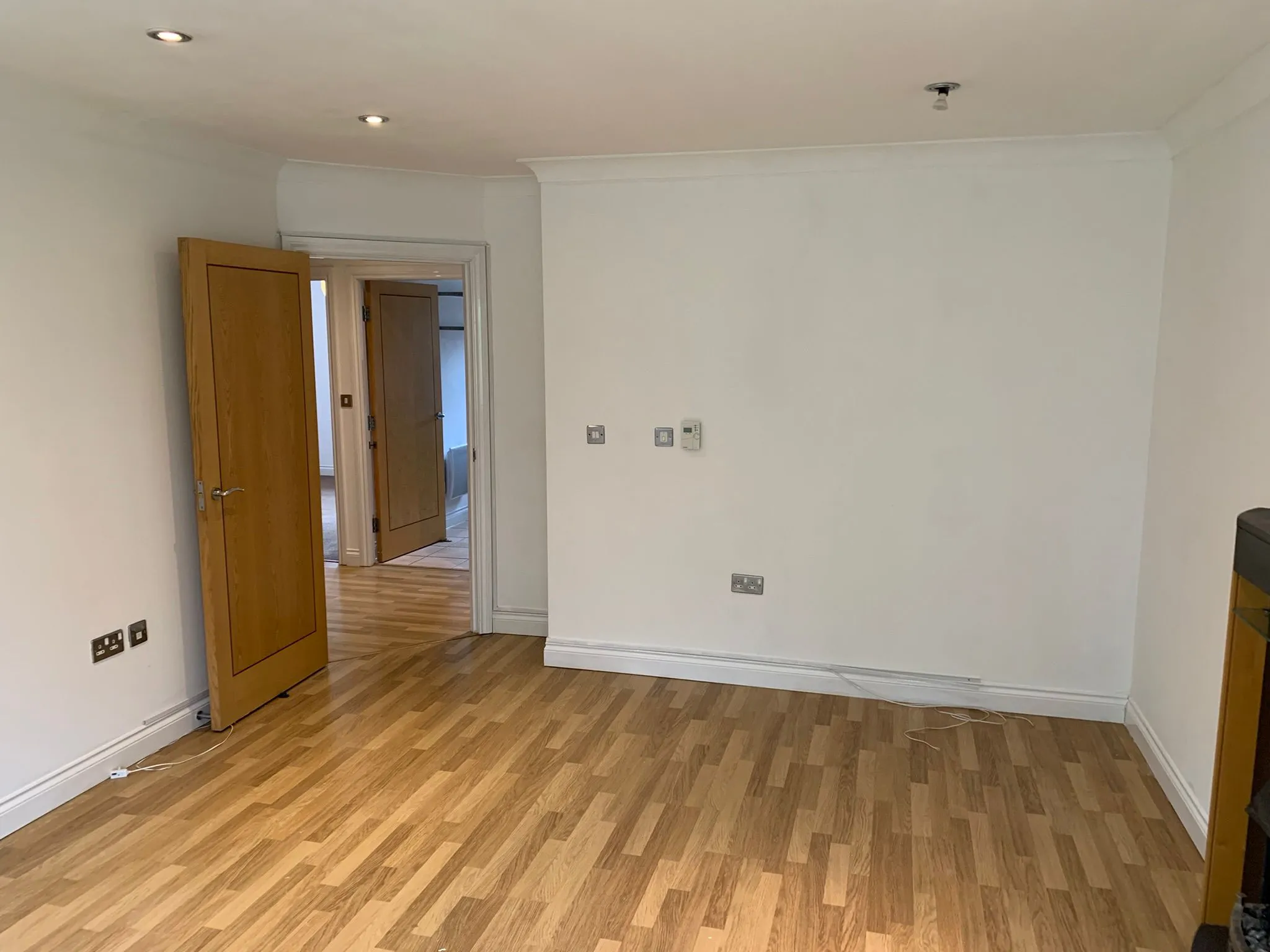 Painting a Garage: Concrete Floor, Walls and Garage Door 2 Plain room with freshly painted white walls, an internal wooden door and laminate flooring, the kind of interior finish that painting a garage conversion aims for | Prestige Painting Solutions